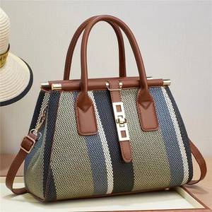 Large multi-color woven tote bag with brown leather trim and golden twist lock clasp