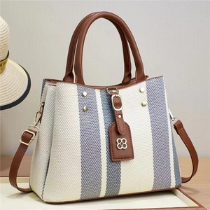 Striped canvas tote bag with brown leather handles and adjustable shoulder strap