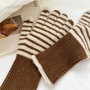 Detail of striped knitted gloves with elastic ribbed cuffs on a cozy aesthetic background