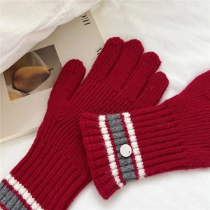Close-up of deep red striped knit gloves with decorative button and wrist stripes