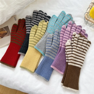 Chic striped knit gloves in various colors on white fabric with cozy autumn vibes