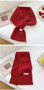 Macro detail of red knitted scarf with texture and woven brand label on white bedding