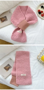 Detail of pink knitted scarf with brown patch, featuring a woven label and soft texture