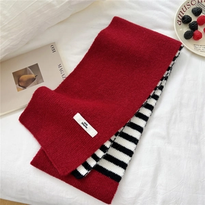 Detailed close-up of thick striped knitted scarf with woven brand tag and red accents
