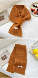 Detail of caramel knit scarf featuring soft bouclé texture and a woven brand label