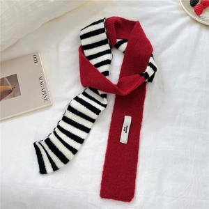Detail of soft striped knit scarf with red contrast and brand label on white fabric