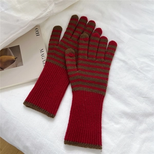 Detail of striped knit gloves featuring red ribbed cuffs and warm thermal texture