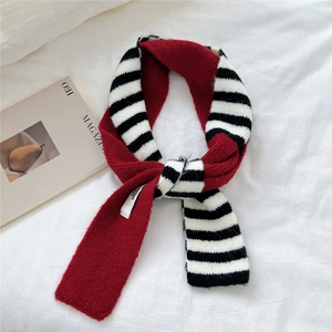 Detail of soft striped knit scarf with contrast stitching on cozy white bedding