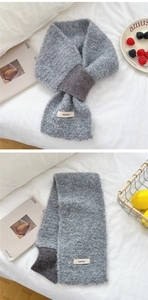 Detail of grey plush knit scarf with cross-over design and white brand label detail