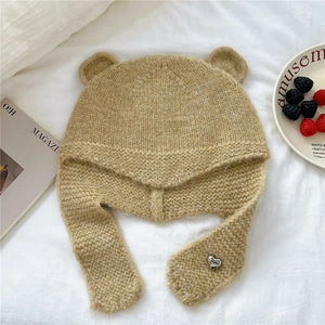 Détail du bonnet en tricot camel avec oreilles d'ours et pendentif coeur en métal