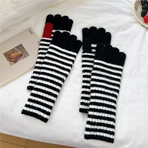 Detailed knit texture of long black and white striped gloves with red fingertip accent