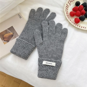 Detailed macro view of gray 100% wool knitted gloves featuring thickened wave-pattern cuffs