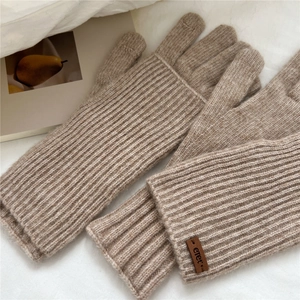 Close-up of knit winter gloves featuring ribbed texture and premium leather logo detail