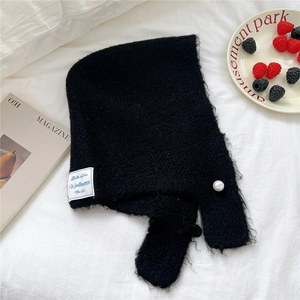 Detail of black knit hood with pearl button closure and woven label on cozy fabric
