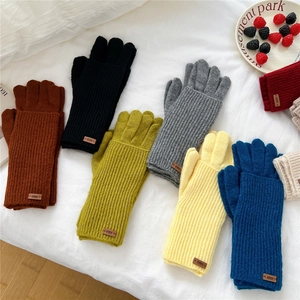 Flat lay of colorful double-layered touchscreen knit gloves with stylish erer leather labels