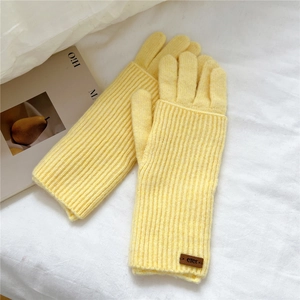 Close-up of bright yellow knitted gloves featuring a textured weave and leather tag