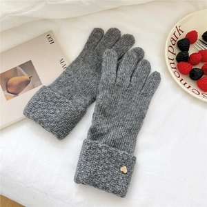 Detailed close-up of dark grey knitted gloves with gold heart charms and ribbed cuffs