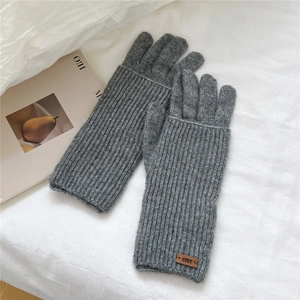 Detailed view of long grey knitted touchscreen gloves with ribbed texture and leather patch