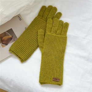 Detailed view of mustard yellow ribbed knit gloves with branded leather patch on white fabric
