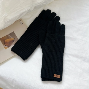 Close-up of black knitted winter gloves featuring long cuffs and a leather logo patch