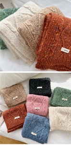 Detail of chunky cable knit scarves in various colors with rectangular woven labels