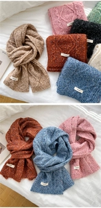 Close-up of thick cable knit winter scarves in multiple colors with brand labels