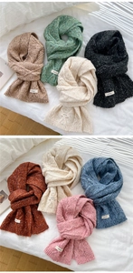 Close-up of thick knit wool scarves showing textured cable knit patterns and fabric tags