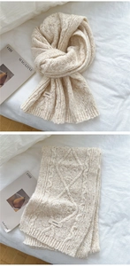 Detail of cream cable-knit scarf showing thick texture and minimalist woven label