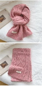 Detail of pink cable knit scarf showing soft wool texture and brand woven label