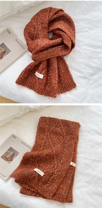 Detail of rust red chunky knit scarf with colorful specks and cable stitch texture