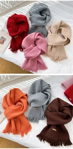Detail of knitted winter scarves with fringe edges and brown Hand Made leather labels