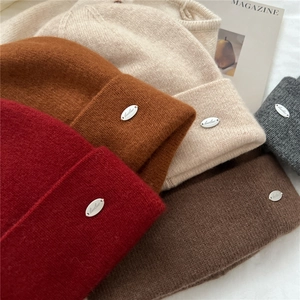 Detailed close-up of knit texture and metal brand plate on colorful winter beanies