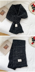 Detail of black and white knit scarf with cross design and ins fabric label