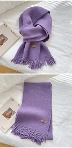 Detail of purple knitted scarf with tassels and a brown leather Hand Made label tag