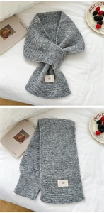 Macro shot of grey knit scarf texture with ins fabric label on white bedding