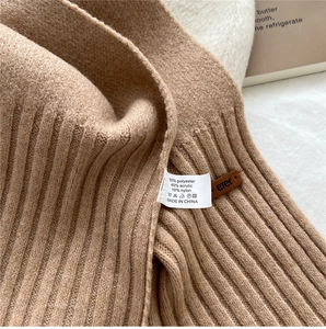 Close-up of beige knitted scarf texture with fabric composition label and brand tag