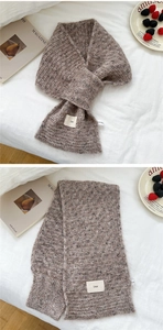 Detail of chunky knit brown scarf featuring cross-tie styling and a minimalist ins label
