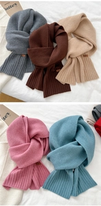 Detailed view of winter knitted scarves in various colors with stylish leather brand tags