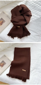 Detail of dark brown knitted scarf with handmade leather tag and fringe texture