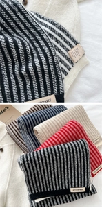 Detail view of striped knit scarf texture and material label with wool blend content