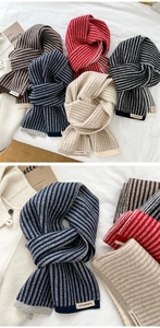 Close-up of soft knitted scarf with two-tone stripes and woven brand label detail
