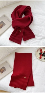 Detail of dark red knitted long scarf with ribbed hem and stylish square woven label