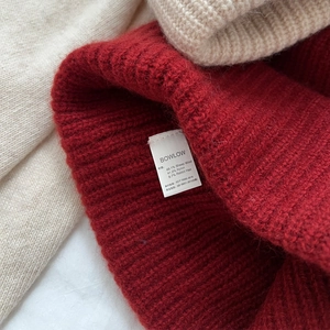 Macro detail of wool blend knit texture and care label showing premium material quality
