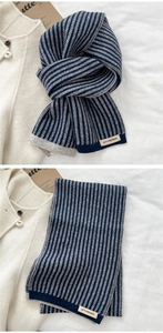 Detail of navy and grey striped knitted scarf featuring the ACT SURPRISE logo tag