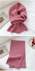 Detail of pink knitted winter scarf featuring thick ribbed texture and vintage brown tag