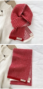 Close-up of red and white striped knitted scarf with ACT SURPRISE label for winter warmth