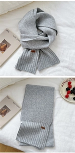 Detail view of light grey knitted scarf with a leather patch and ribbed texture
