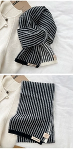 Detail of black and white striped knit scarf showing soft texture and brand label