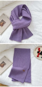 Detailed view of light purple knitted winter scarf with ribbed edges and leather label