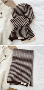 Detail of striped knit scarf showing rich texture and ACT SURPRISE woven brand label